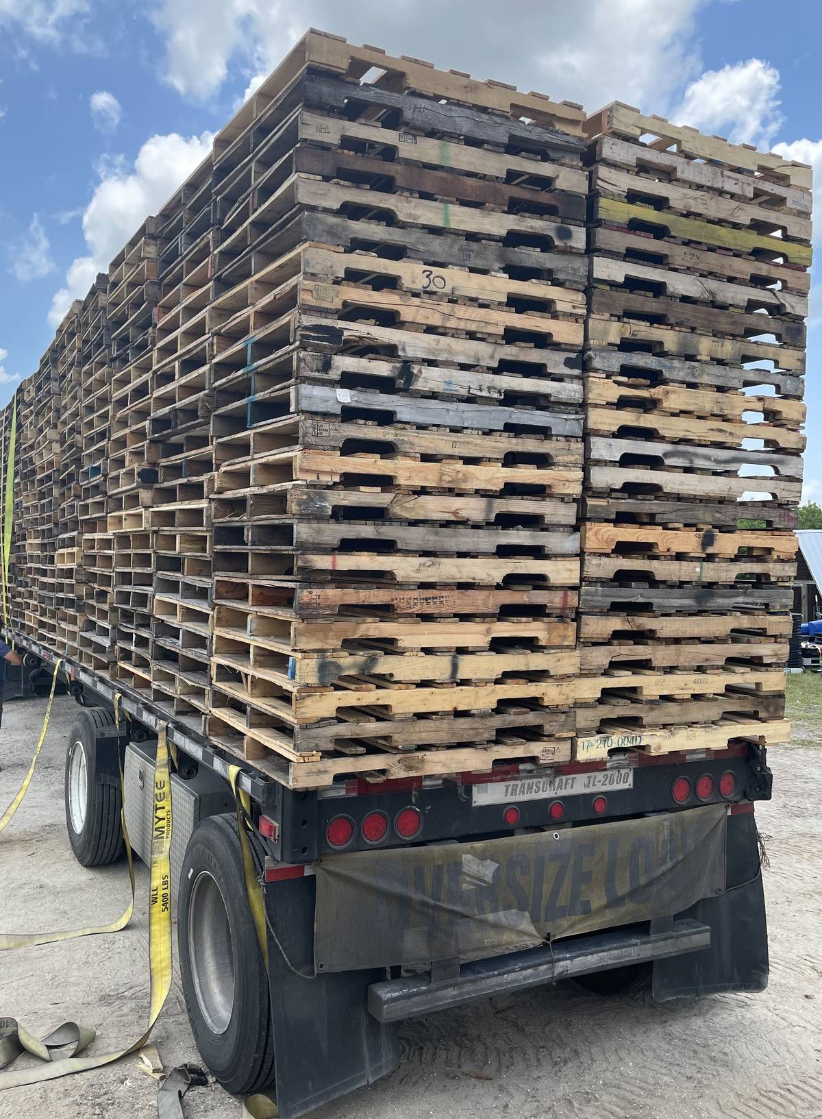 Flatbed truck fully loaded with wood pallets stacked high for Florida delivery